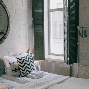 A cozy and stylish bedroom featuring modern decor and a sunlit window with shutter panels.