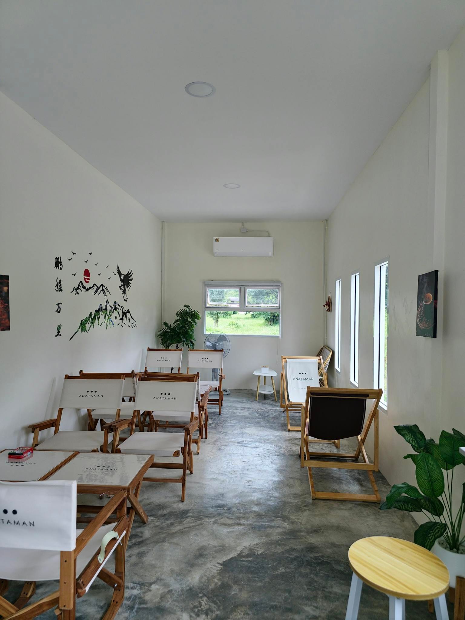 A modern, minimalist cafe interior featuring wooden furniture and potted plants.